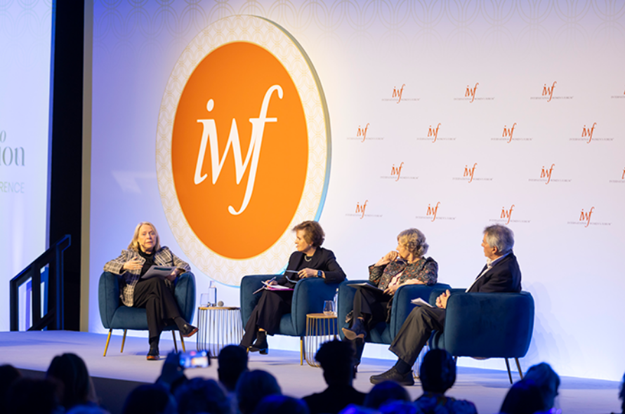 Four panelists seated in blue chairs on a conference stage, with a large orange circular logo featuring a white 'if' behind them and a backdrop with repeating logos; audience visible in the foreground.