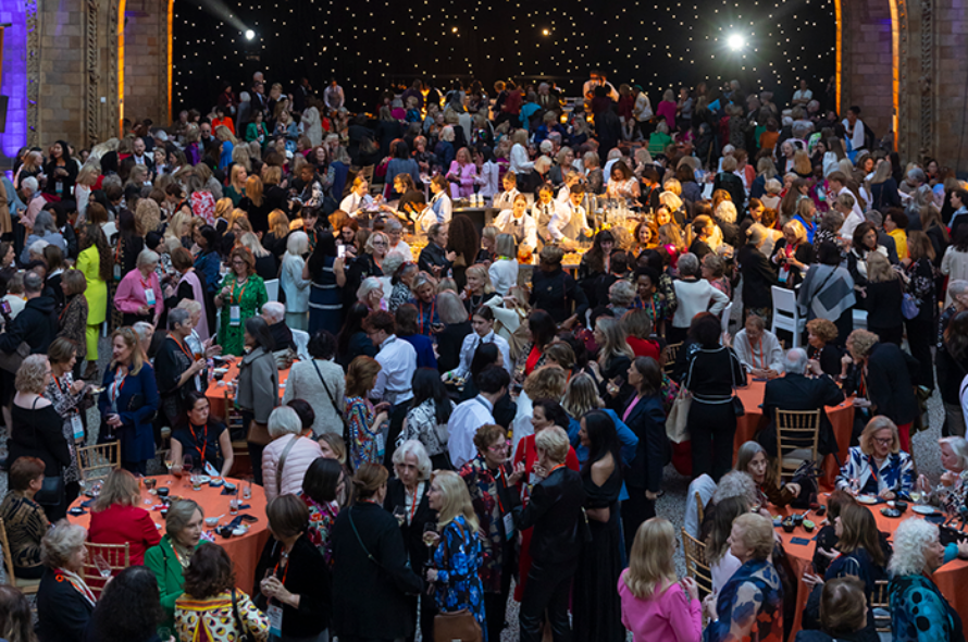 Crowded banquet hall filled with guests dining at round tables under twinkling lights.